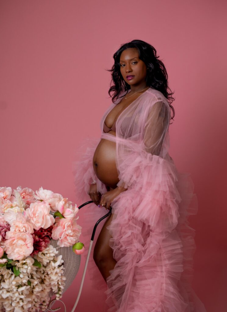 Expecting Mom posed with baby carriage in maternity photoshoot.