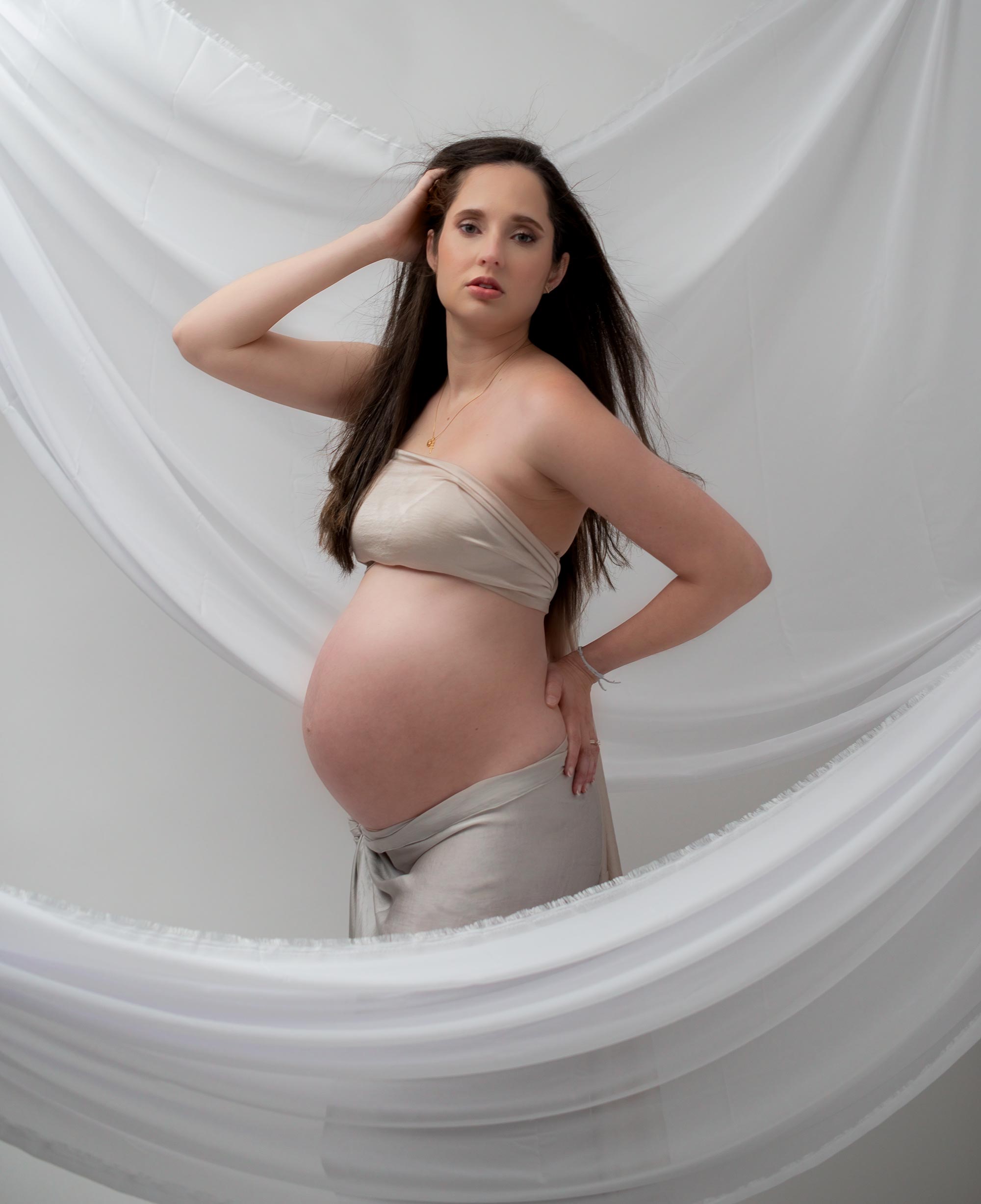 Expecting Mom in the DMV area posing in an ethereal and draped with fabric around.