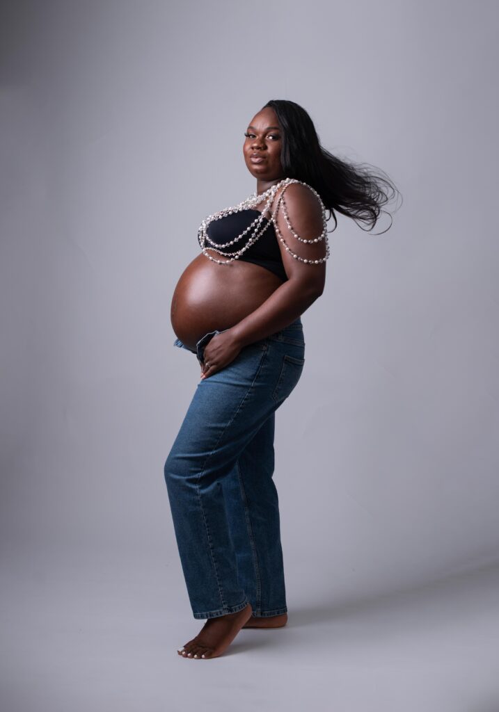 Expecting mom wearing a custom bejeweled top for a High Fashion Maternity Photoshoot with Jeans.