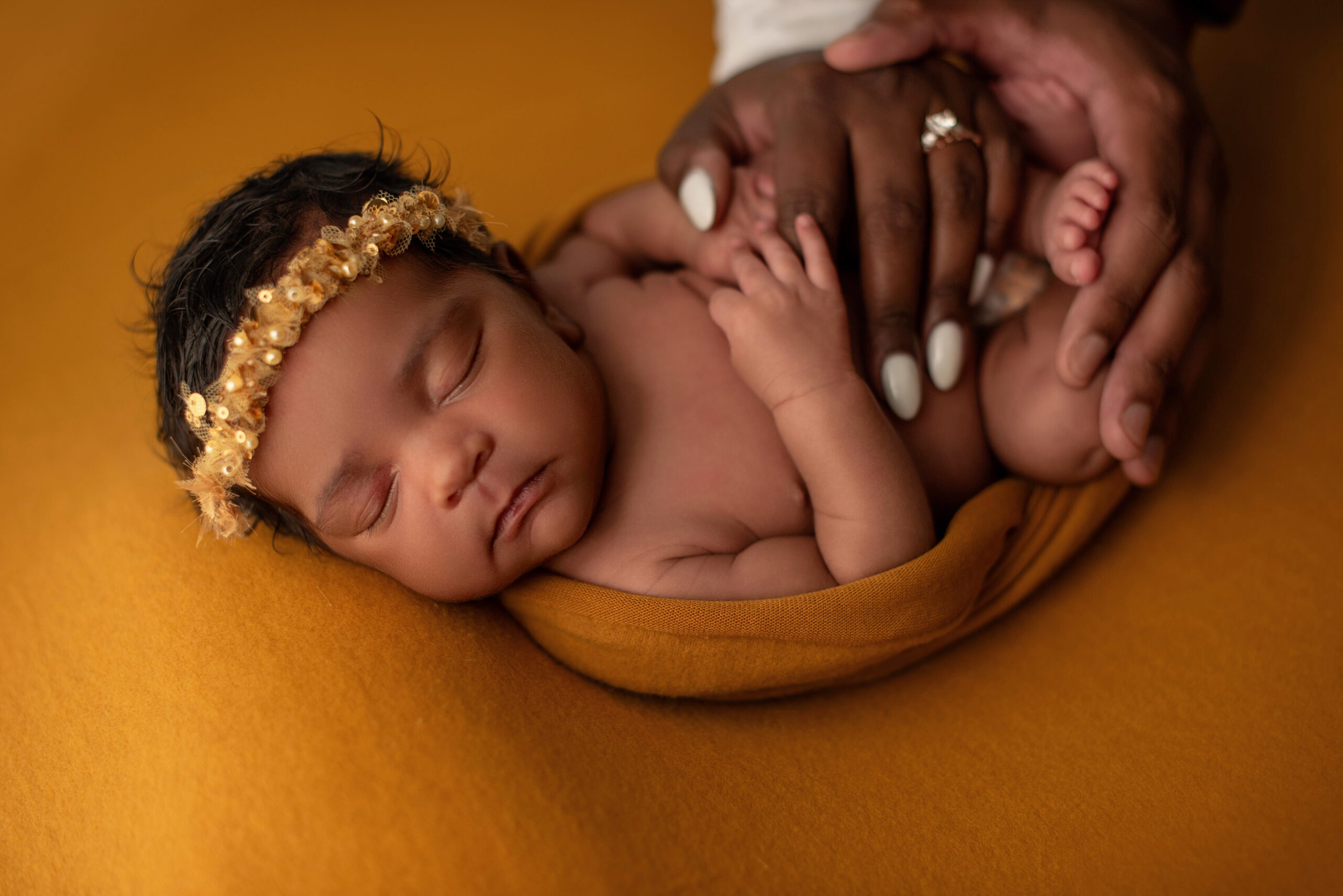Parents hands on baby for hand poses in a home newborn session