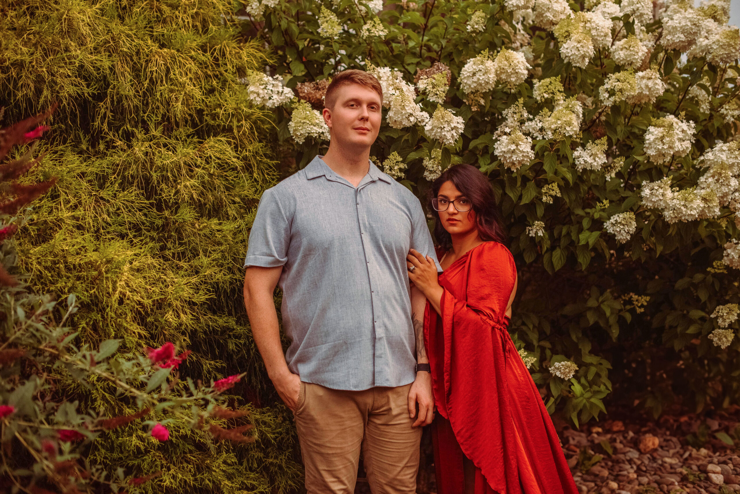 A couple in front of a flower bush for their family fall photoshoot.