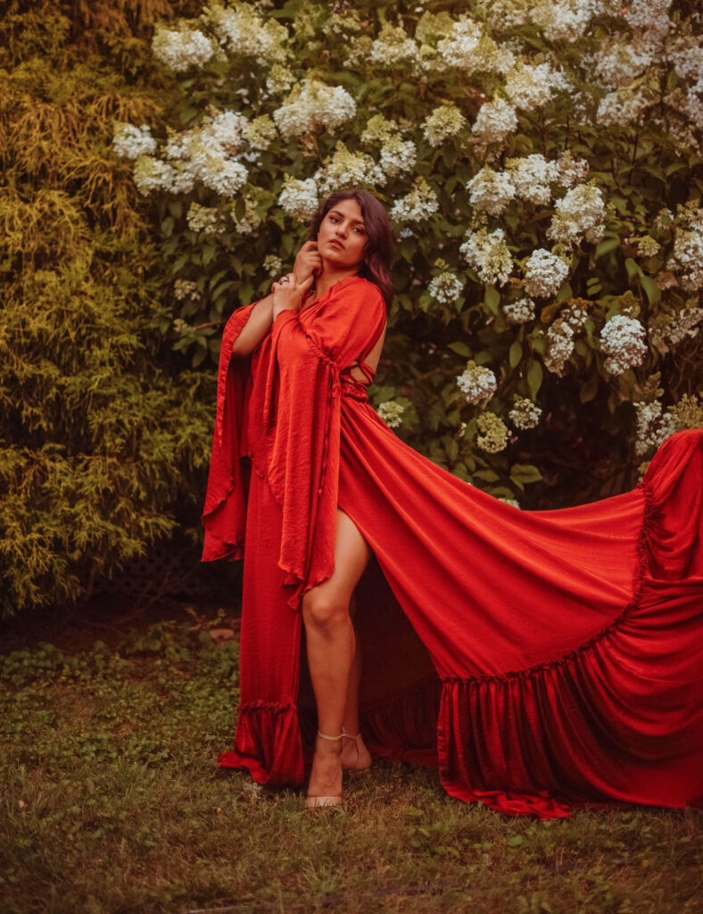 Mom styled in a burnt orange gown for her fall family photoshoot standing in front of bushes.